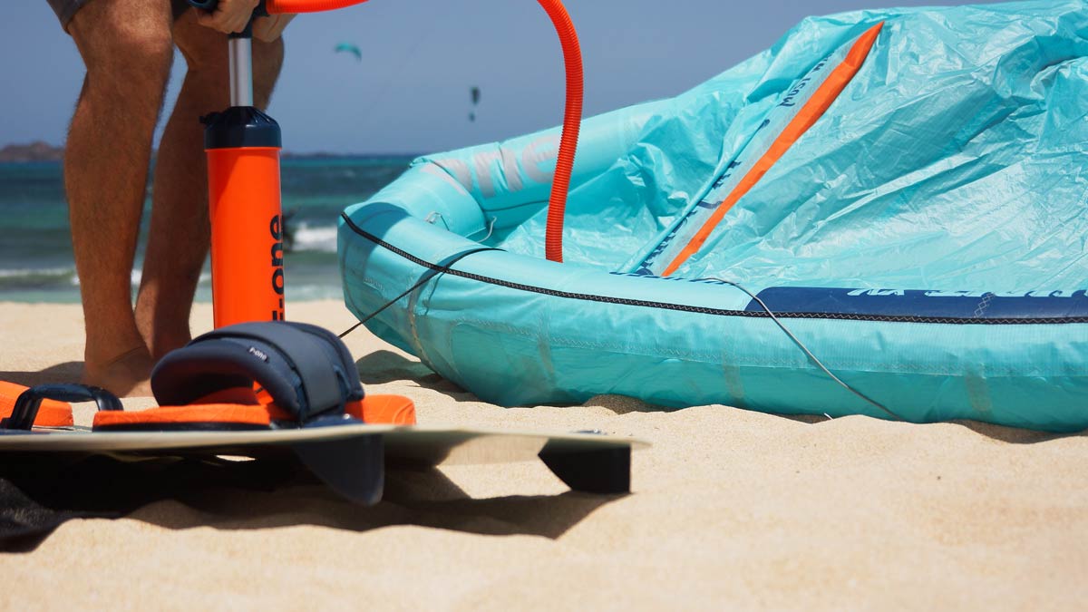 Fase di gonfiaggio dell'ala e preparazione della tavola sulla sabbia di Fuerteventura per una lezione di kitesurf.