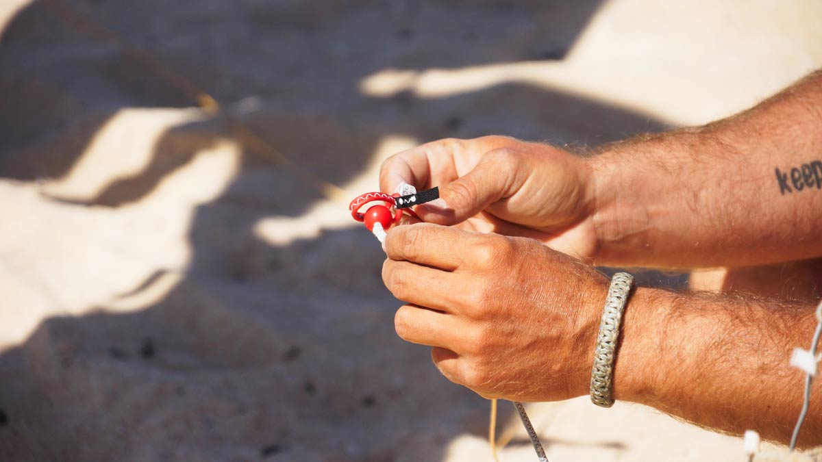 Istruttore di kitesurf di CKite prepara i sistemi di sicurezza e le linee del kite sulla sabbia di Corralejo per una lezione principianti.